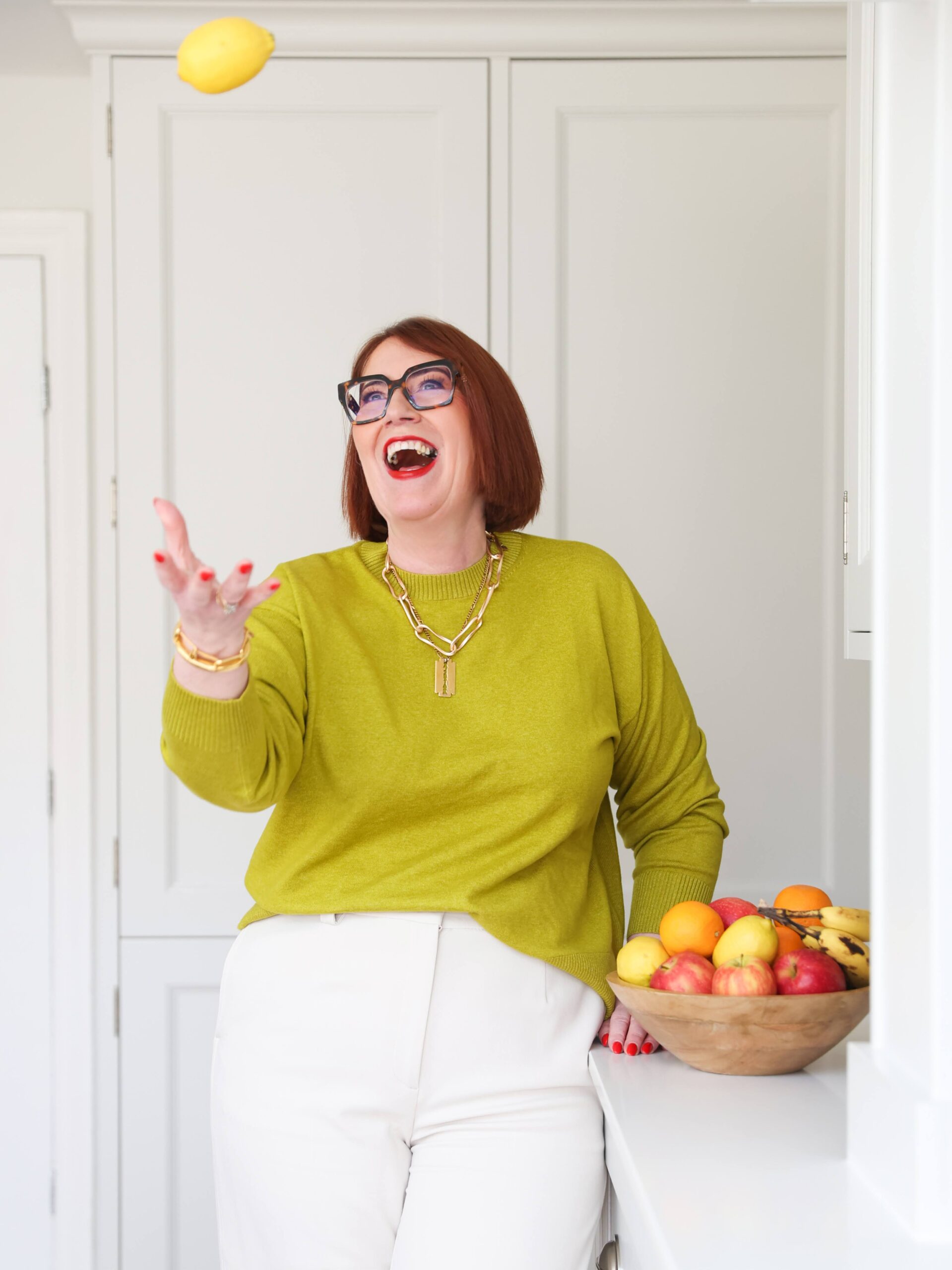 This image is of Jane in the kitchen, throwing an apple into the air, and laughing.